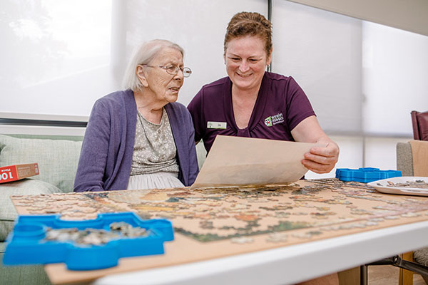 Image representing jobs and careers at Wesley Mission Queensland, Brisbane. It shows staff and aged care senior resident playing a puzzle game