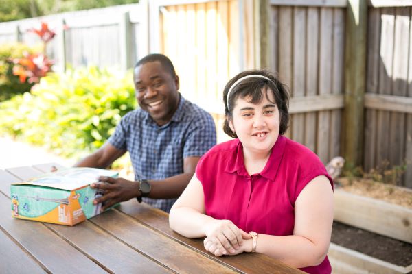 Happy young man and woman with disability sitting outdoors in a sunny day
