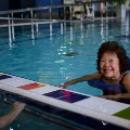 Lady smiling in pool while wearing flotation equipment