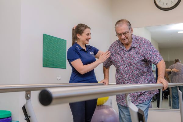 Physiotherapist helping client on exercise equipment