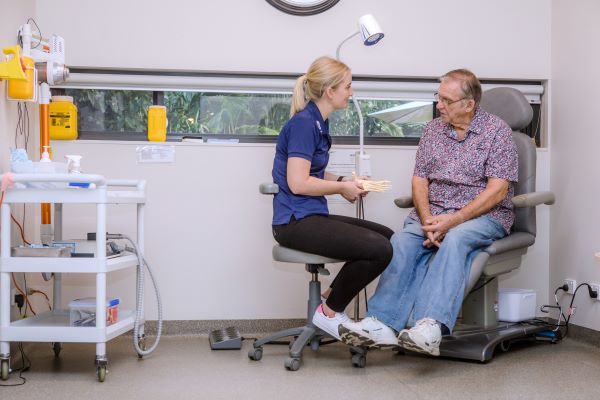 Podiatrist showing client a model of the foot in a clinic environment