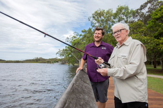 Elderly man fishing with his support worker