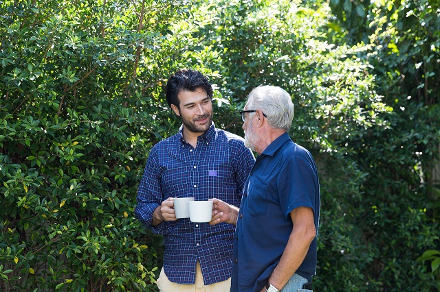 An older and younger man walking and talking in a park