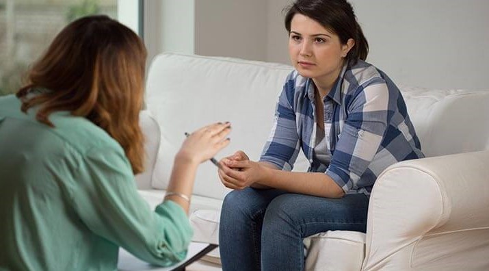 Two people sit talking on couches