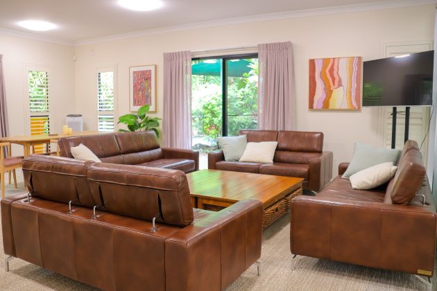 A living area with four leather couches and a TV