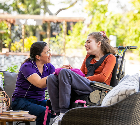 Hummingbird House staff member and guest Worker and teenager smiling in the garden of Hummingbird House, Queensland’s only children’s hospice
