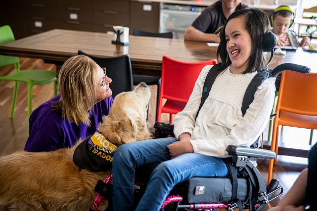 Hummingbird House client in wheelchair with therapy dog