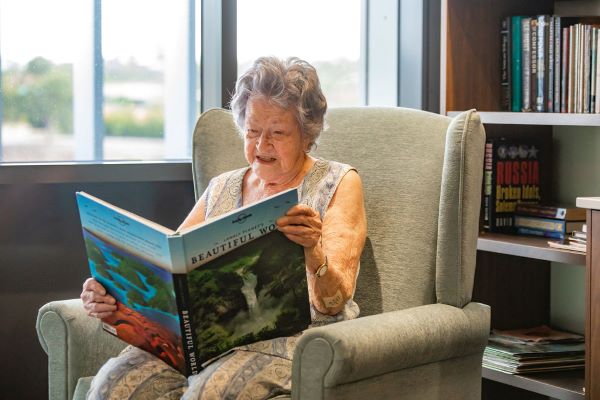 Resident reading in armchair by window at Dovetree Aged Care Nursing Home in Brisbane