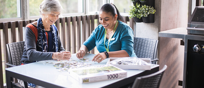 Resident and support work enjoying a puzzle