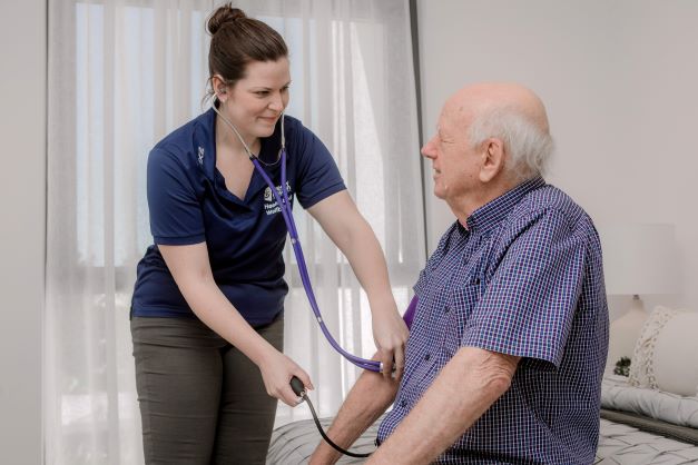 A nursing staff examines one of our aged care resident