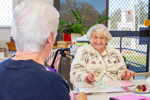 Two elderly ladies smiling and participating in arts and crafts