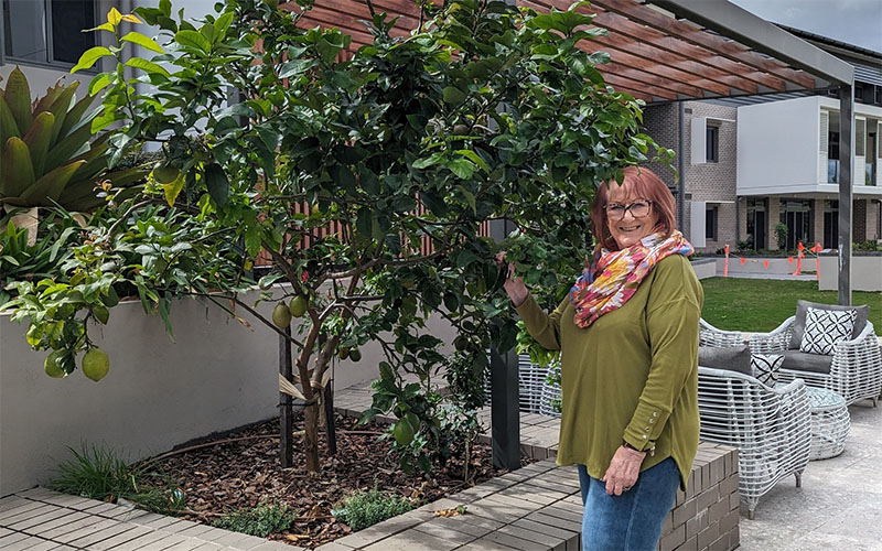 New resident Tania in Rosemount retirement village's green communal outdoor area