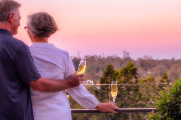Resident couple enjoy champagne and city views on their balcony at Rosemount
