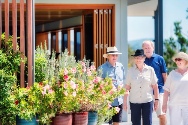 A group of retirees walking outside past flowers in pots