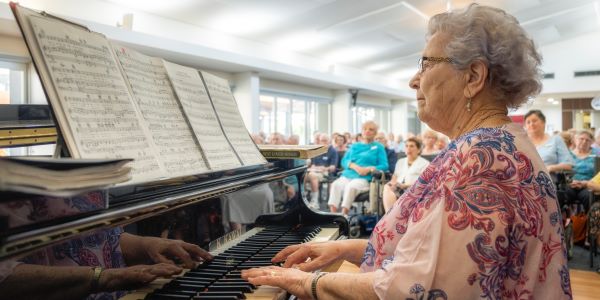 Lady sits at piano entertaining retirees