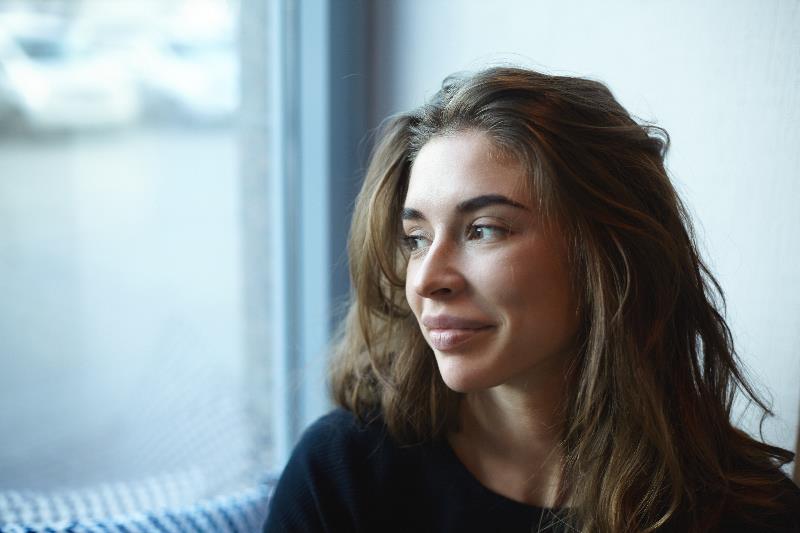 Woman looks out window with slight smile