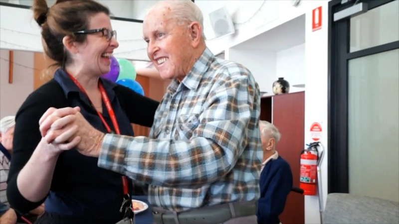 Aged care worker laughing as she dances with a WMQ resident